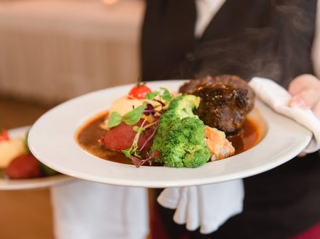 Kellner mit Teller im Restaurant am Burggraben Mecklenburgische Seenplatte