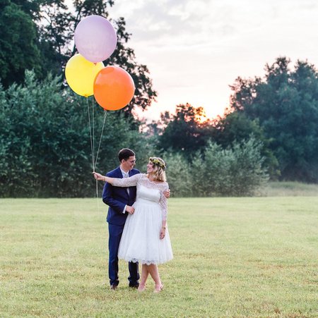 Hochzeitspaar mit Ballons auf dem Gut